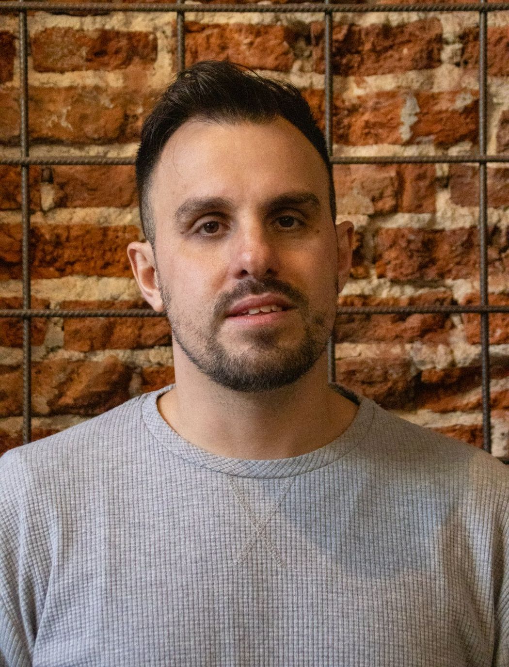 Portrait of Alan Longo, poker performance coach, against a brick wall